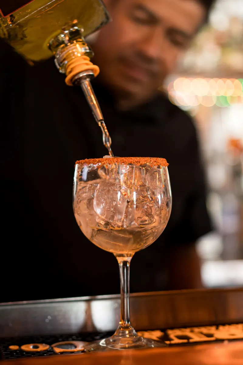 Bartender pouring a cocktail with a chili-salt rim